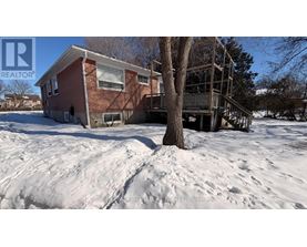 A house with a red brick exterior is surrounded by snow.