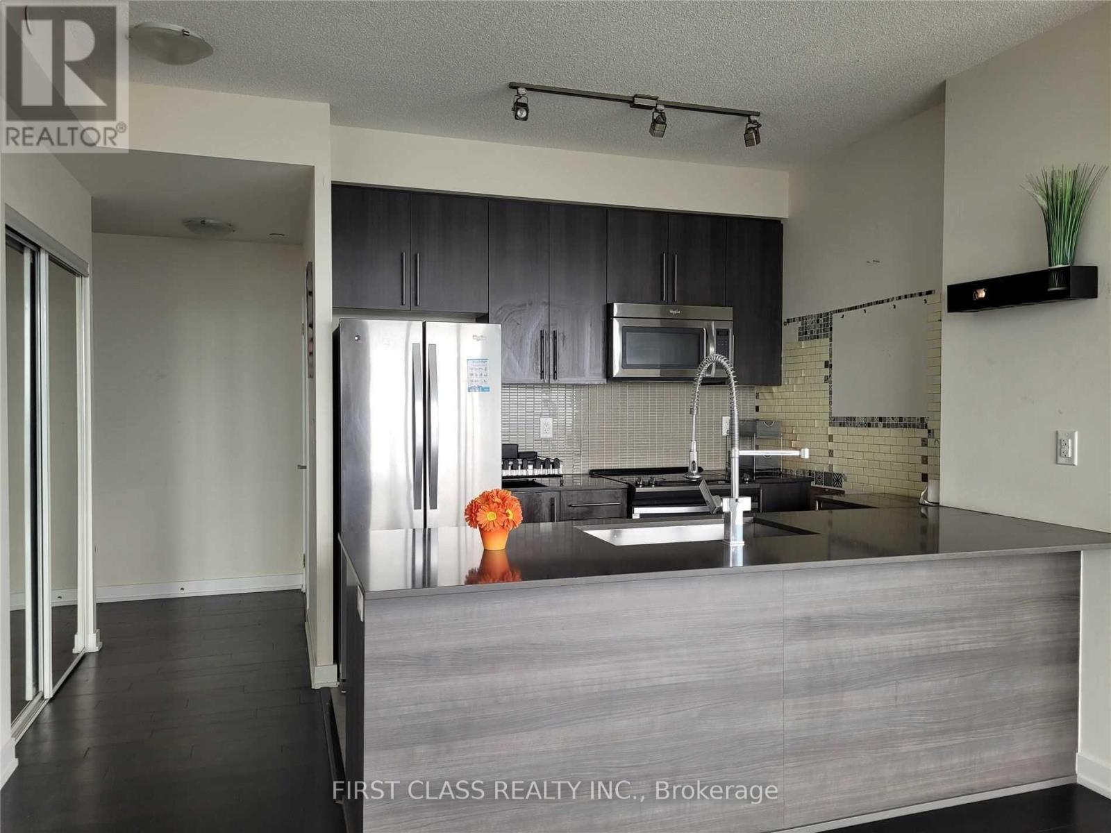 A kitchen with a refrigerator, microwave, and oven.