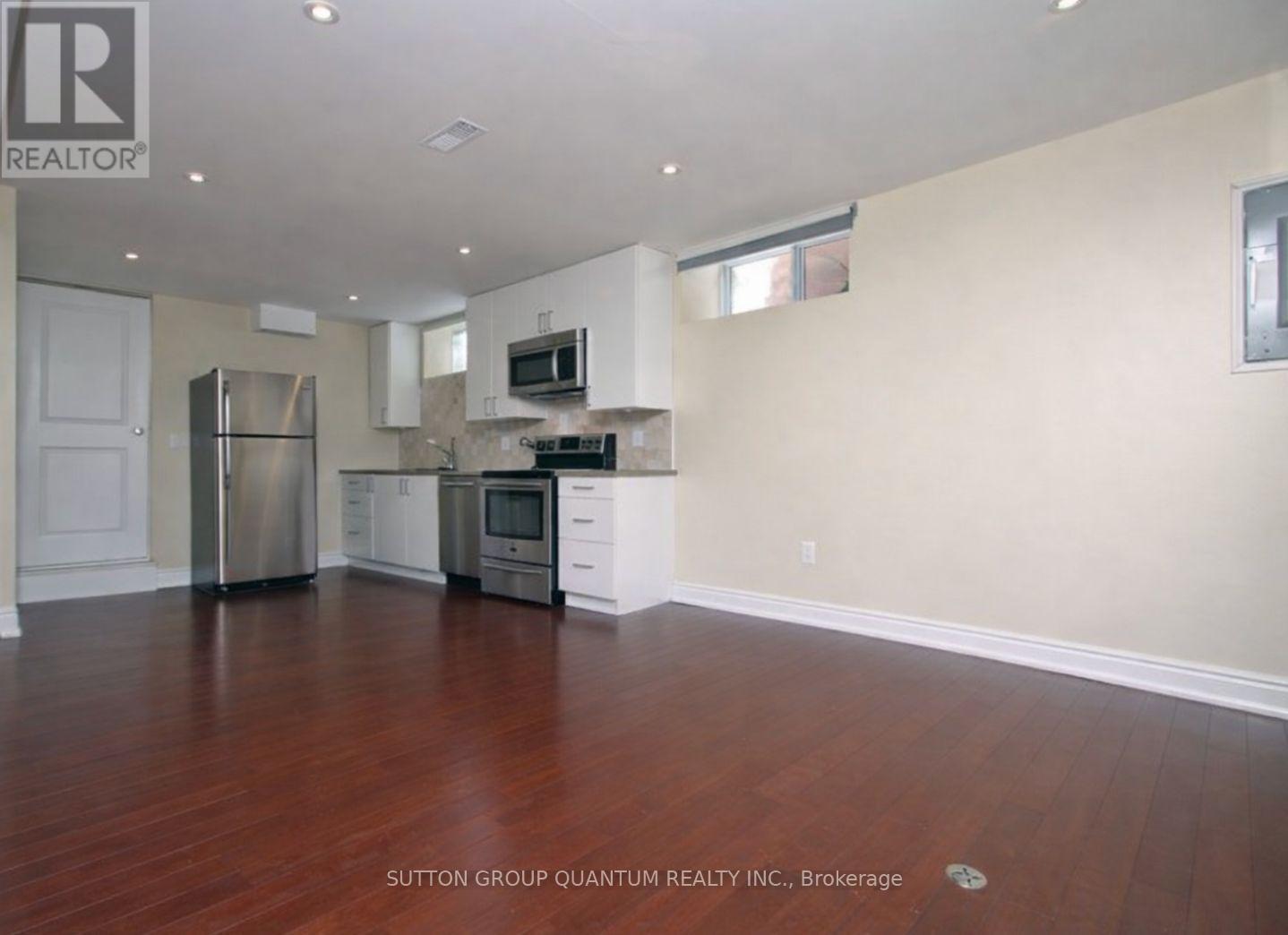 A kitchen with white appliances and a wooden floor.