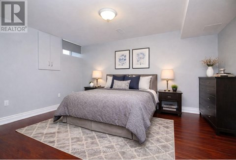 A bedroom with a large bed and a wooden floor.