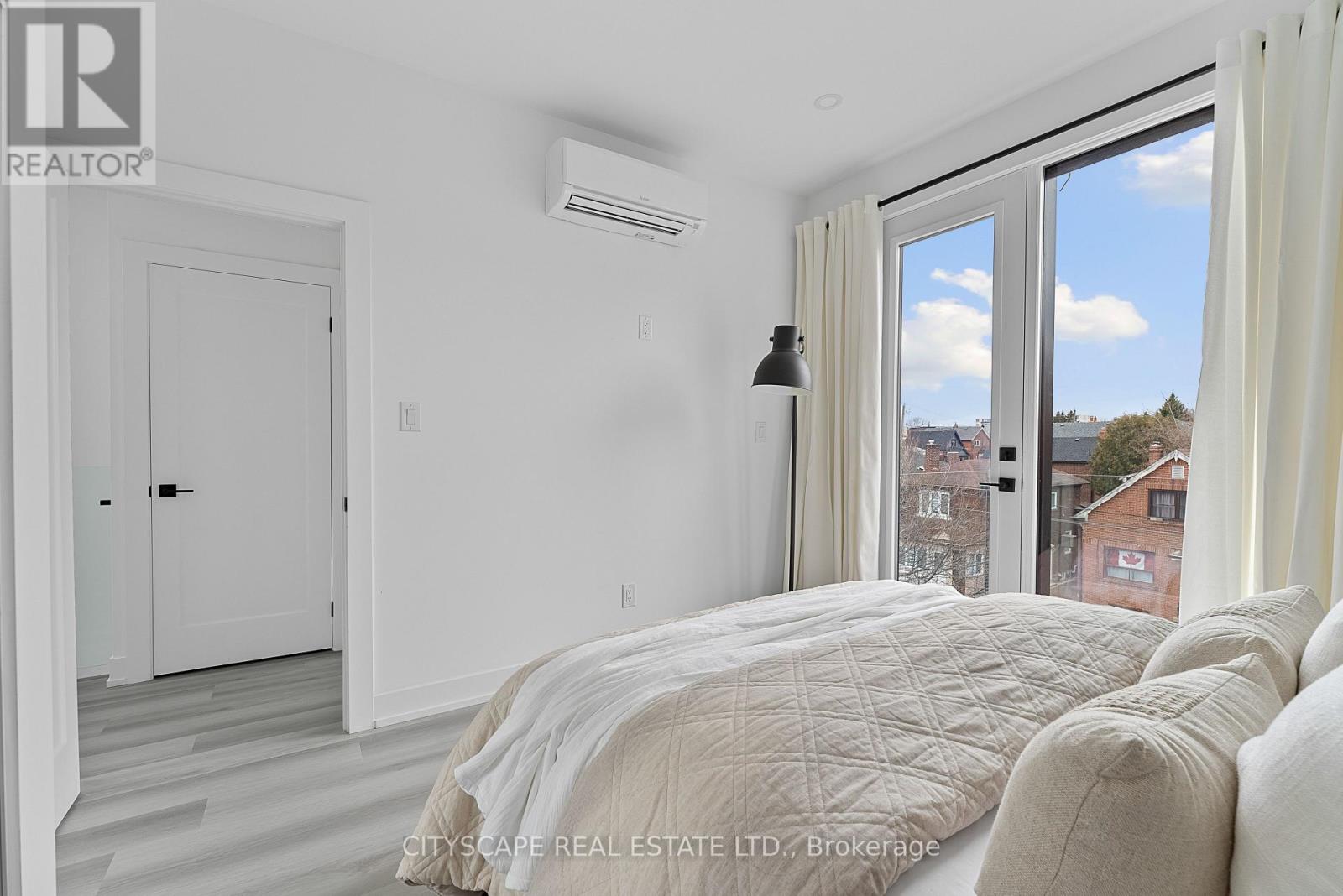 A bedroom with a large bed and a window overlooking a cityscape.