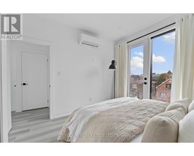 A bedroom with a large bed and a window overlooking a cityscape.