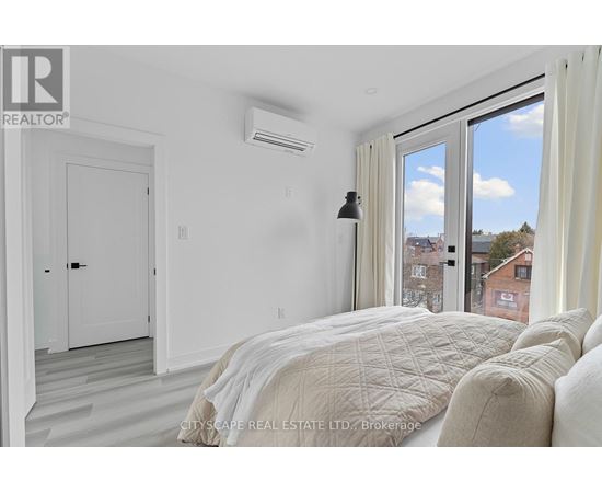 A bedroom with a large bed and a window overlooking a cityscape.