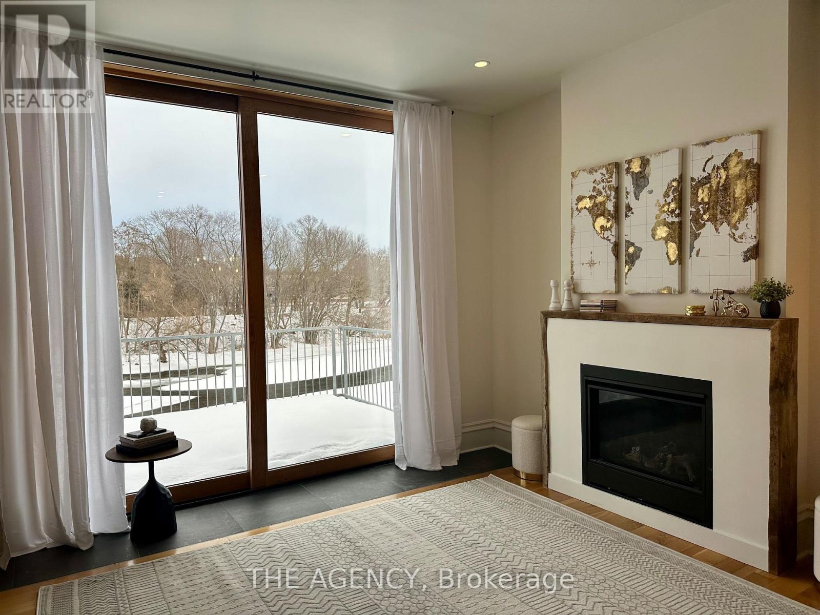A living room with a fireplace and a view of a snowy landscape outside.