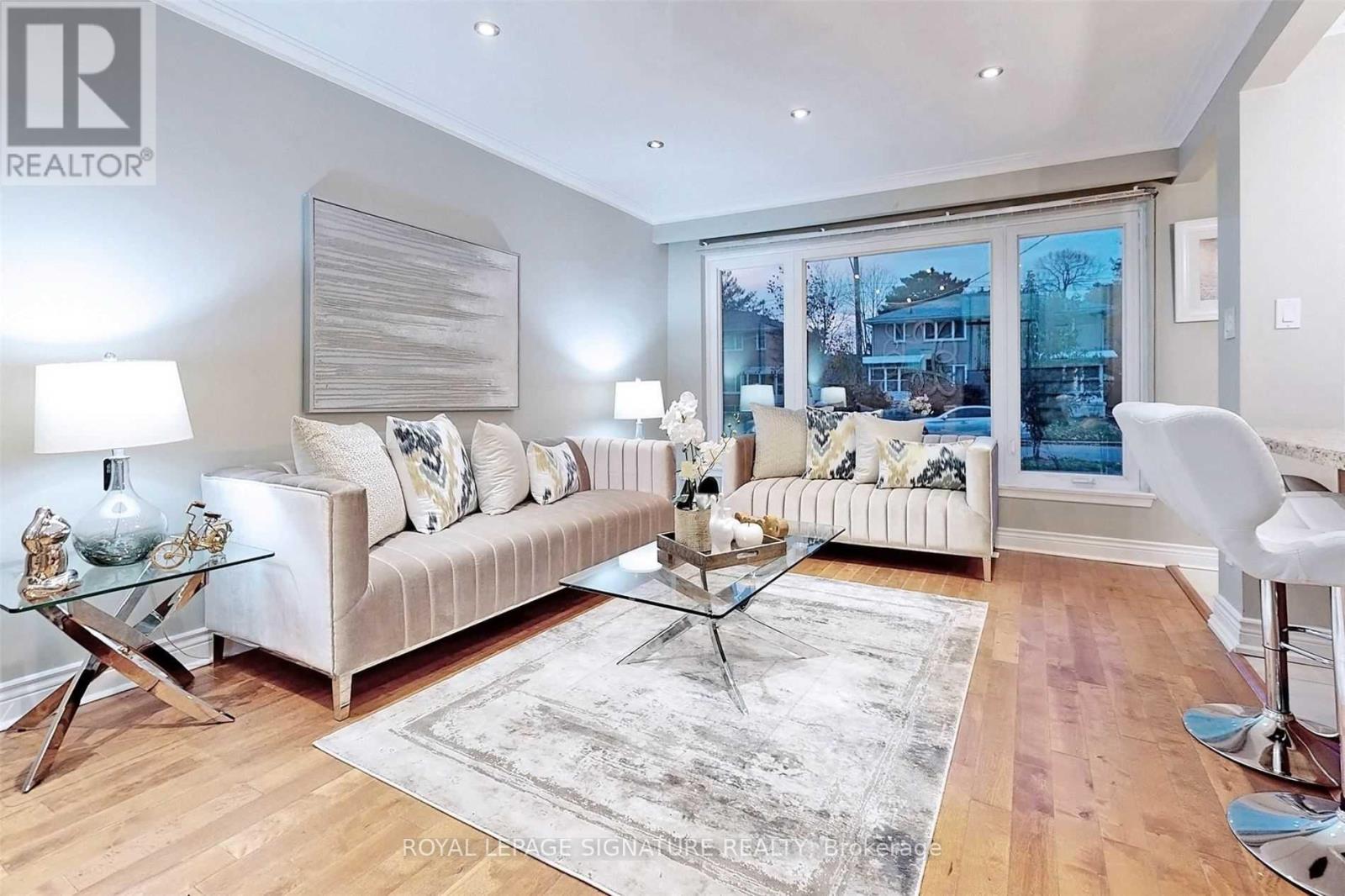 A living room with a white couch and a glass coffee table.