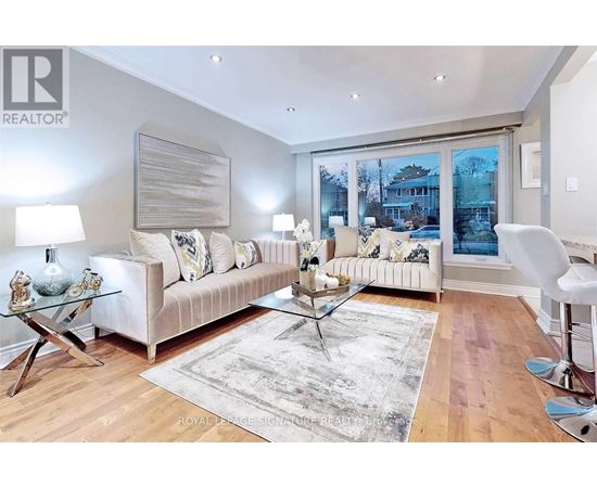 A living room with a white couch and a glass coffee table.