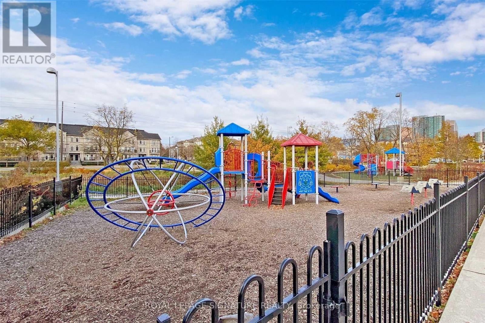 A playground with a blue and red swing set and a black fence.