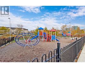 A playground with a blue and red swing set and a black fence.