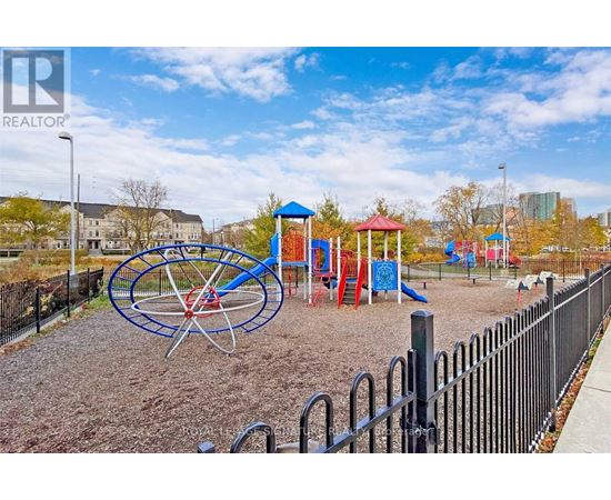 A playground with a blue and red swing set and a black fence.