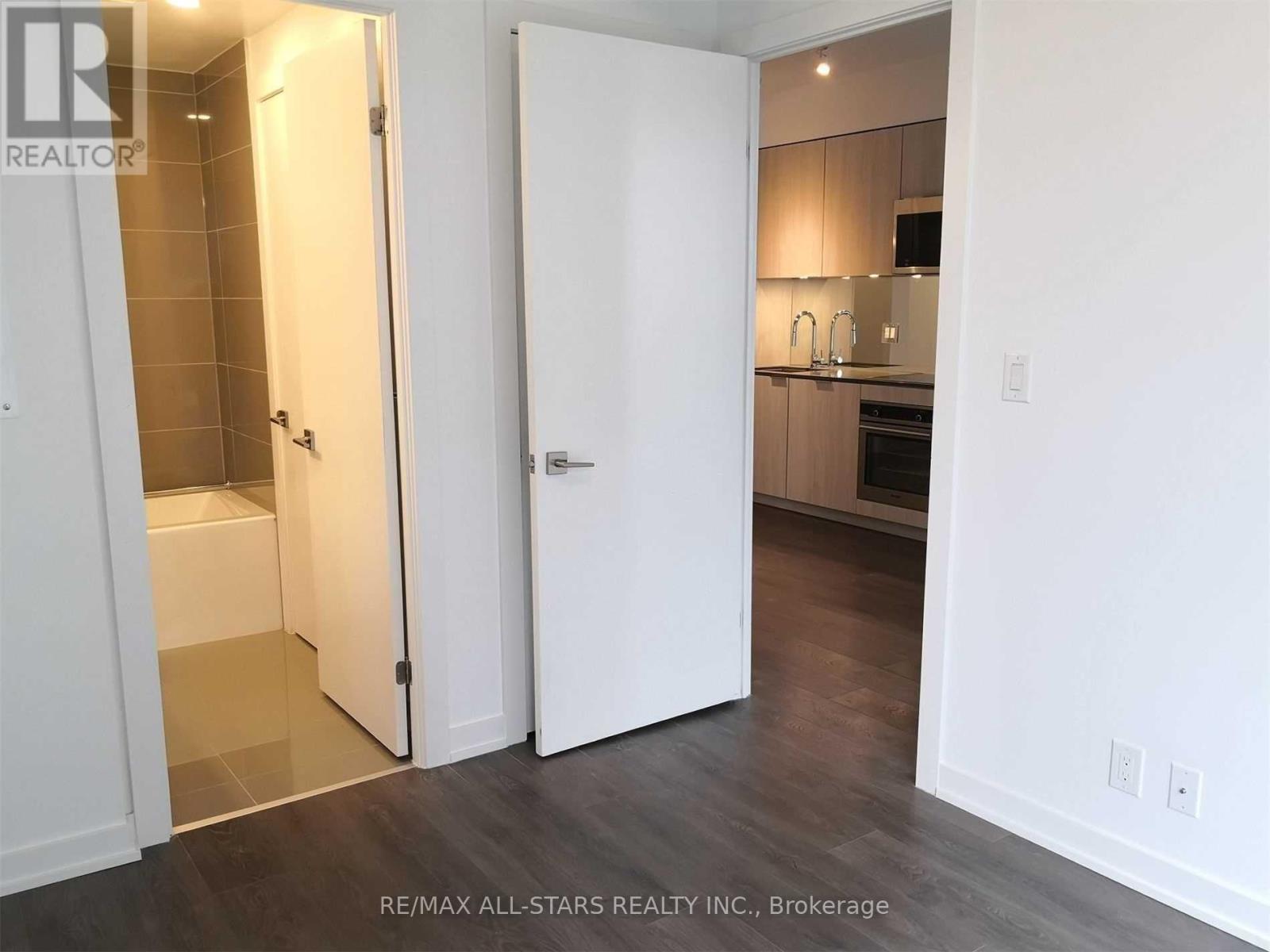 A white door is open to a kitchen.