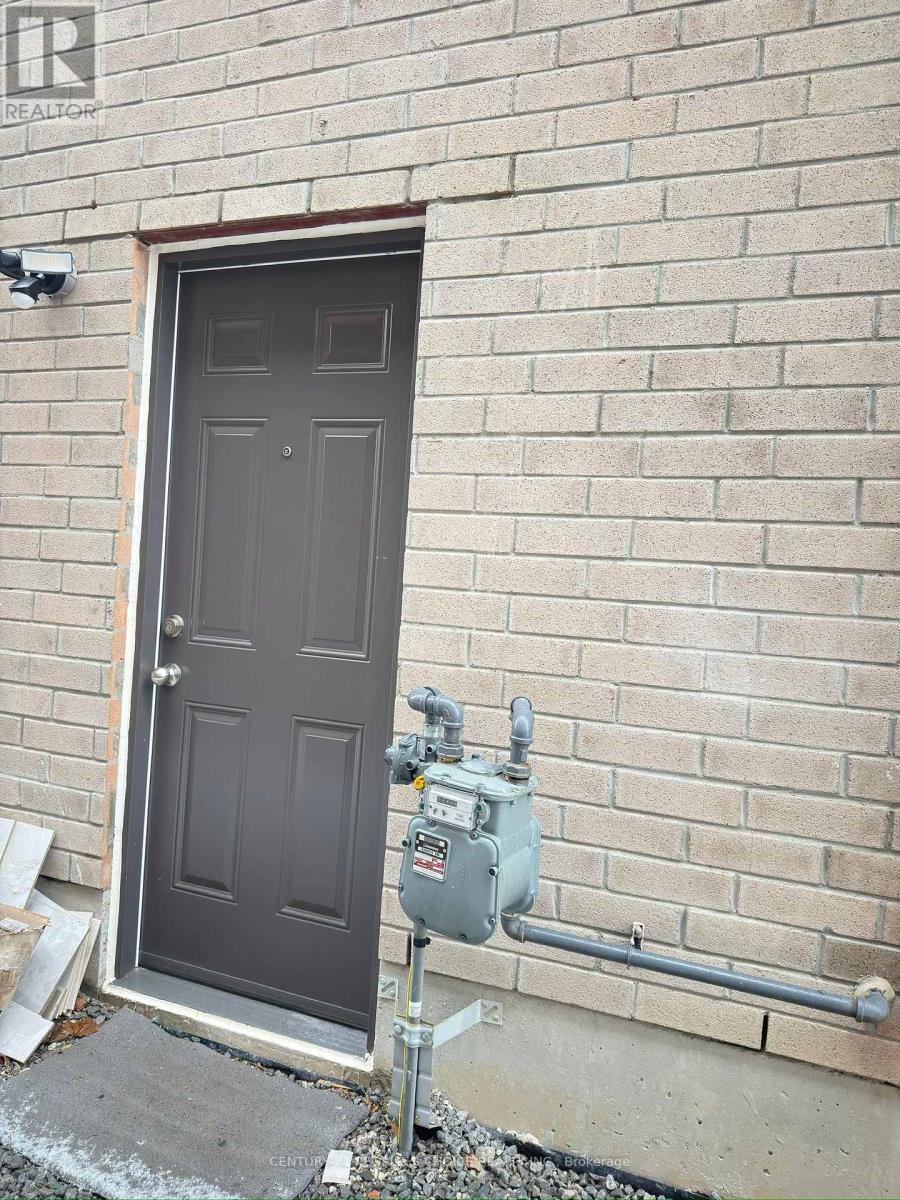 A grey door is open to a brick wall.
