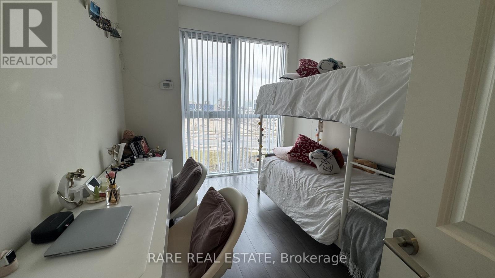 A bedroom with a bunk bed and a desk with a laptop on it.
