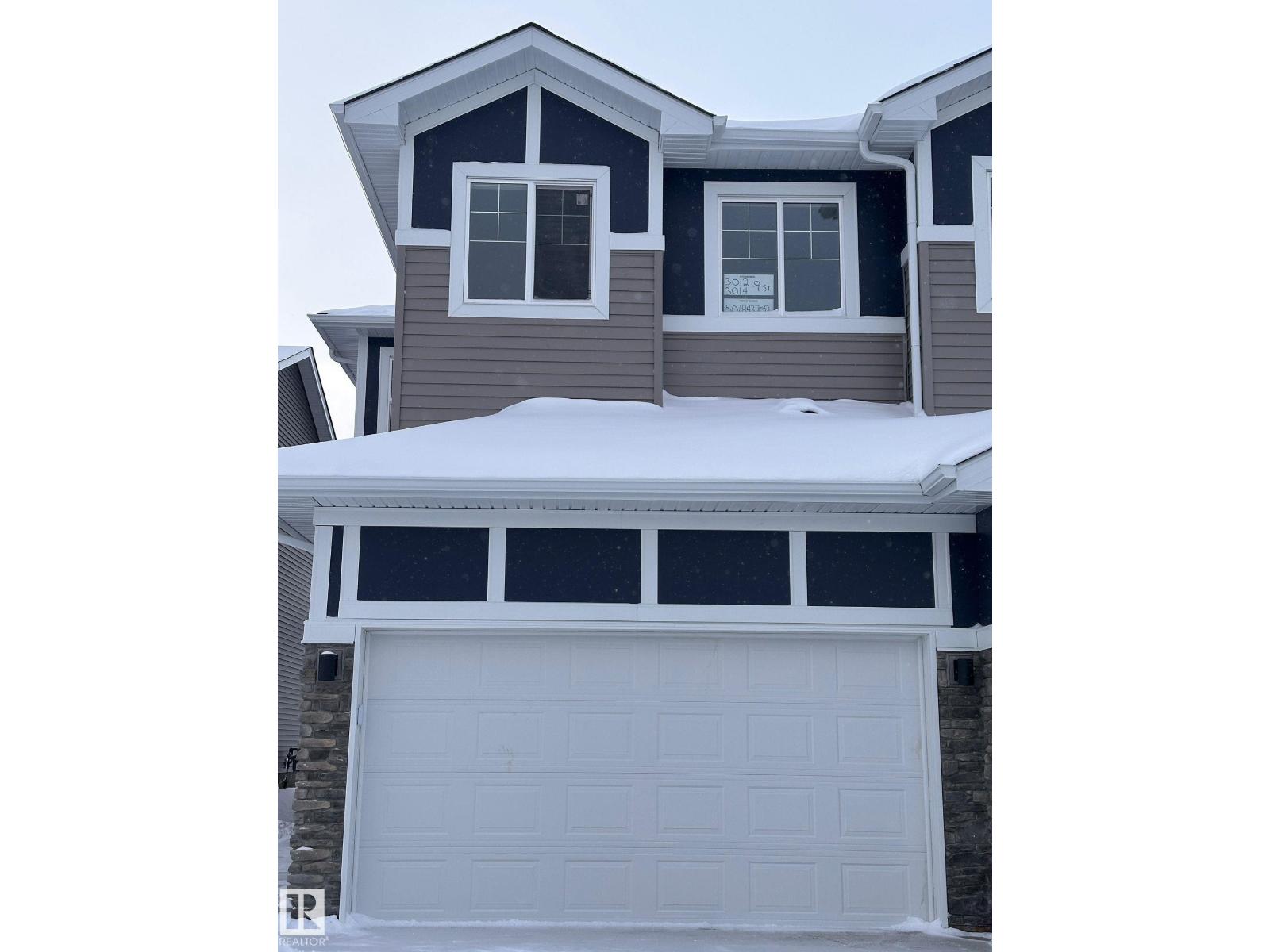 A house with a garage door in front of it.