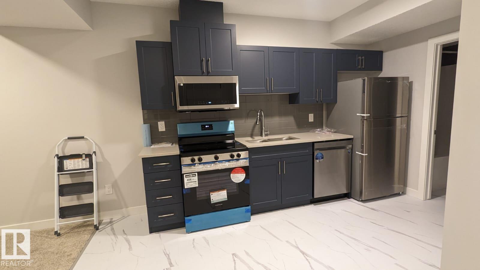 A kitchen with dark blue cabinets and stainless steel appliances.