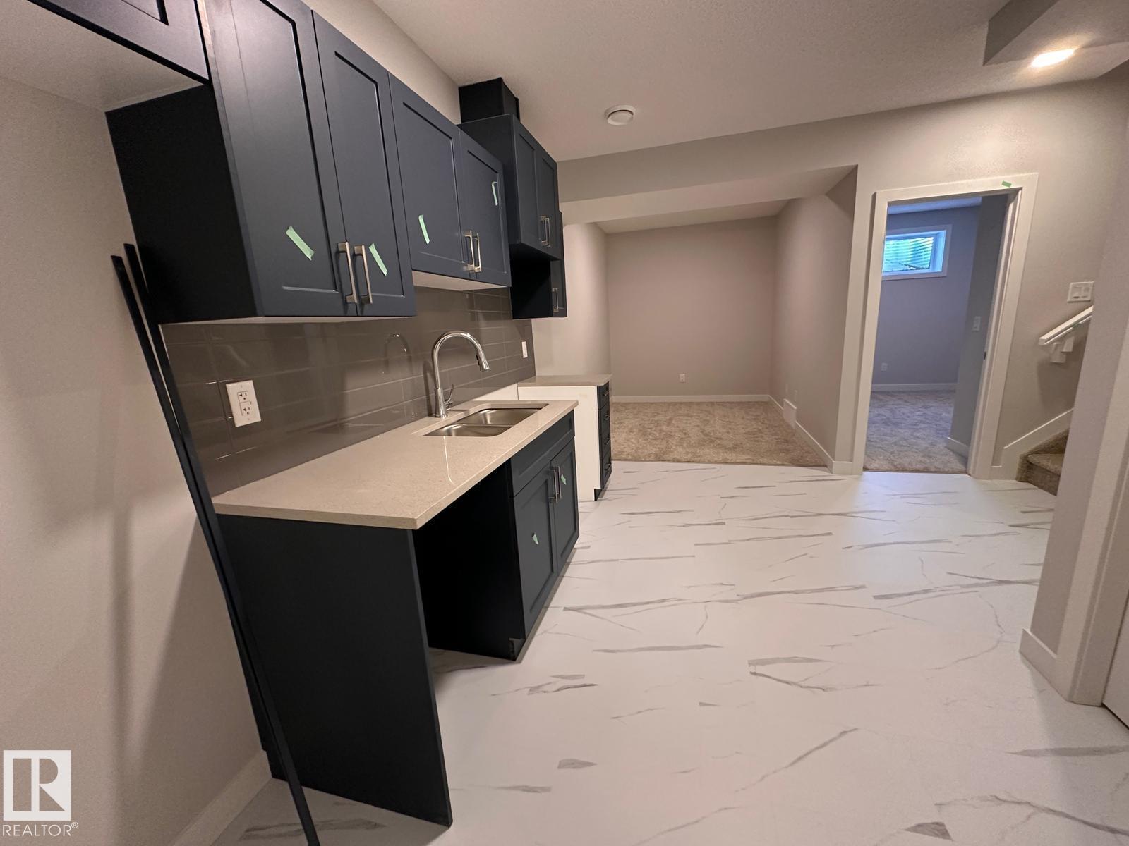 A kitchen with black cabinets and a marble floor.