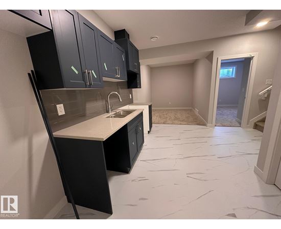 A kitchen with black cabinets and a marble floor.