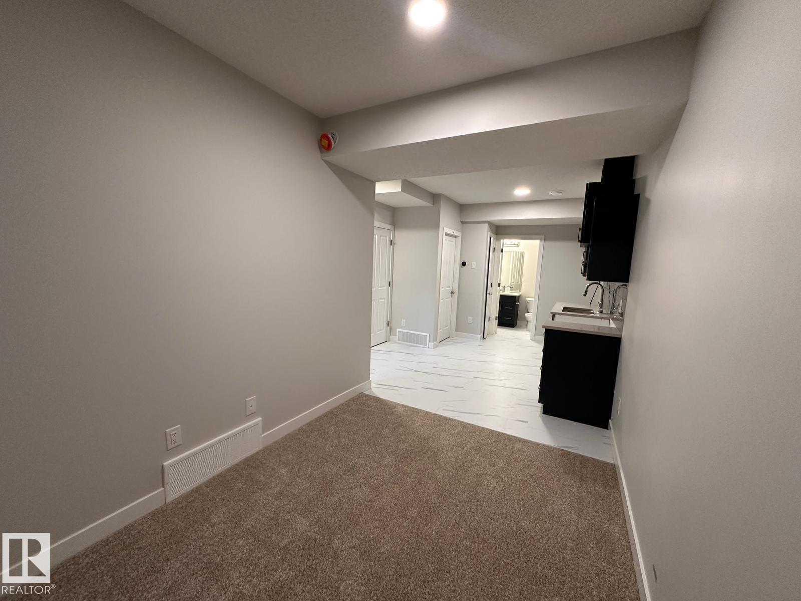 A large, empty room with carpeted flooring and white walls.