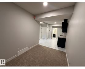 A large, empty room with carpeted flooring and white walls.