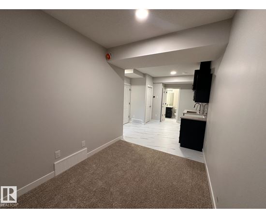 A large, empty room with carpeted flooring and white walls.