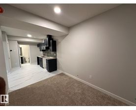 A room with a carpeted floor and a wall-mounted television.