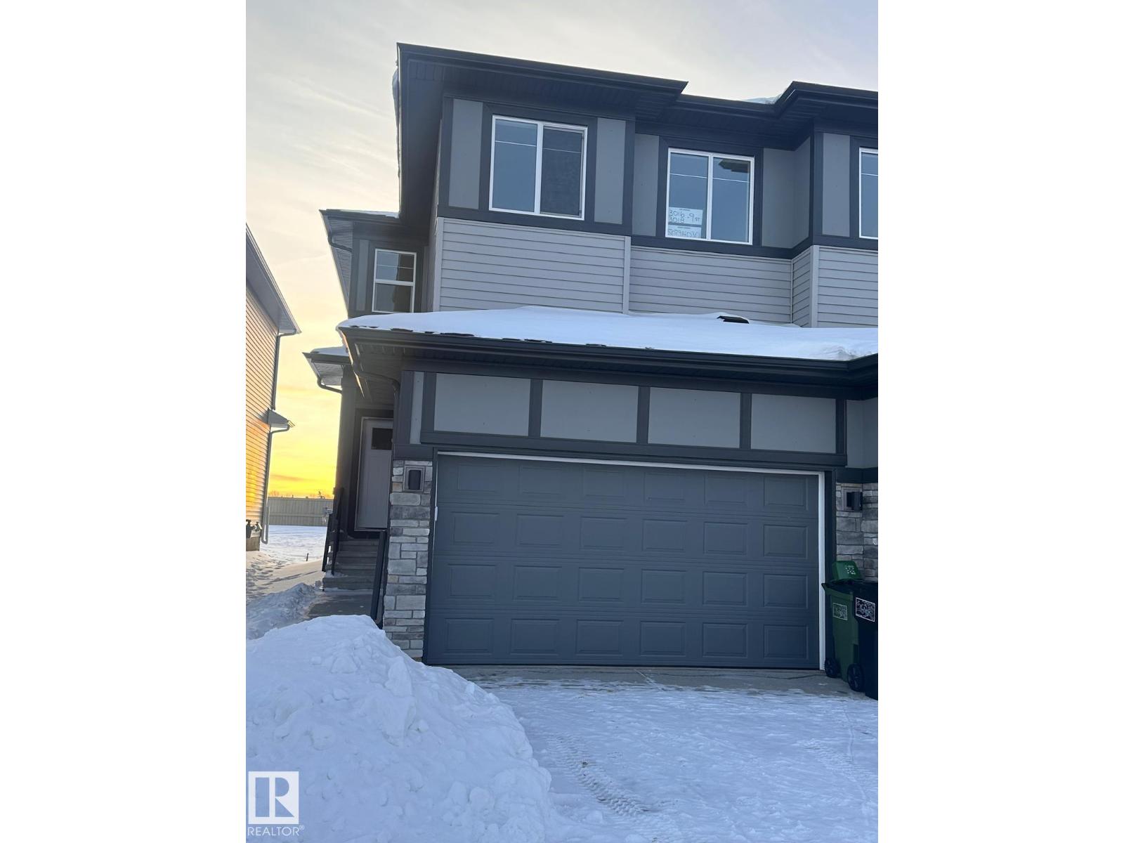 A house with a grey garage door in front of it.