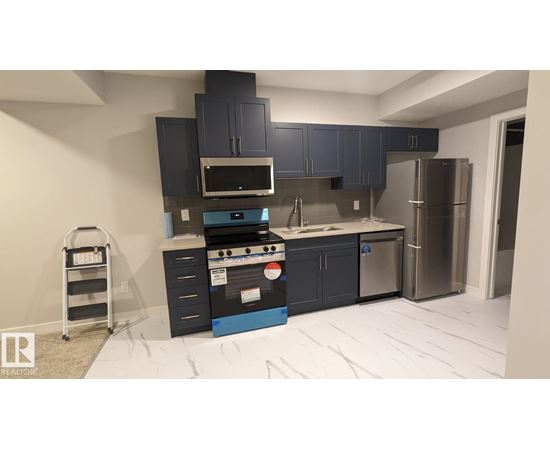 A kitchen with dark blue cabinets and stainless steel appliances.