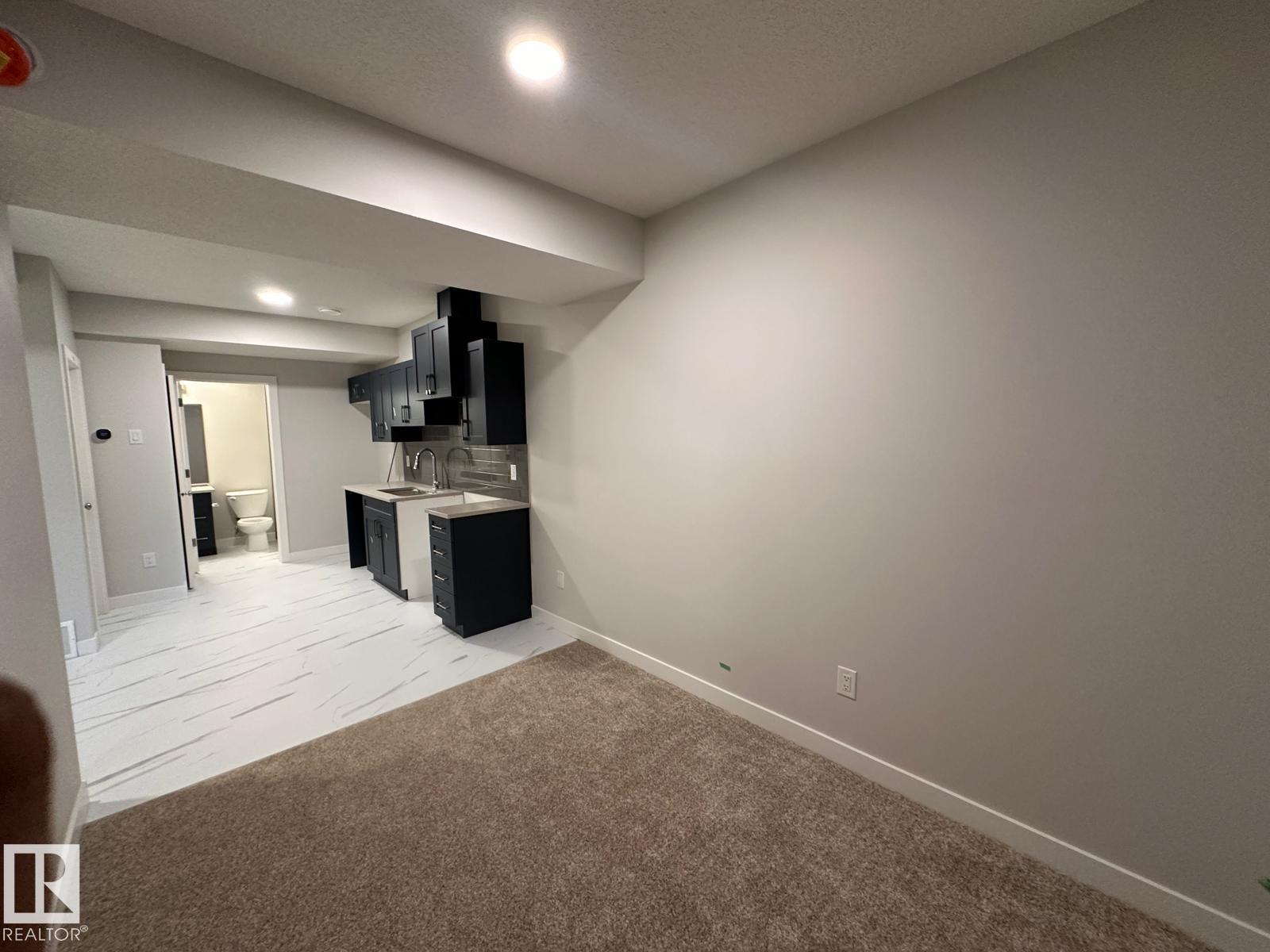 A room with a carpeted floor and a wall-mounted television.