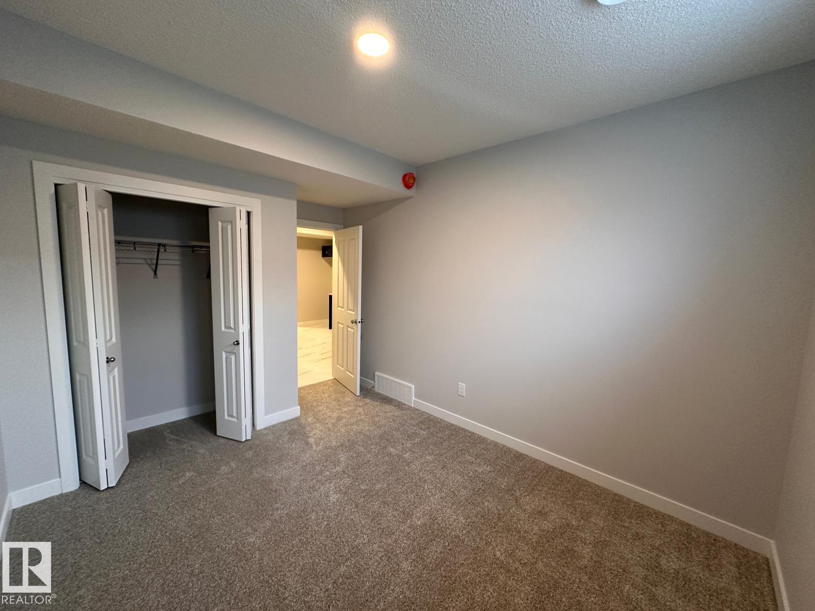 A room with a carpeted floor and a doorway leading to another room.