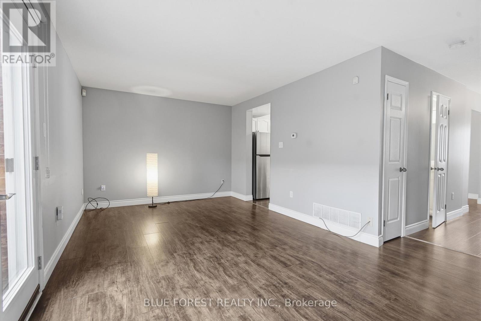 A spacious room with wooden flooring and white walls.