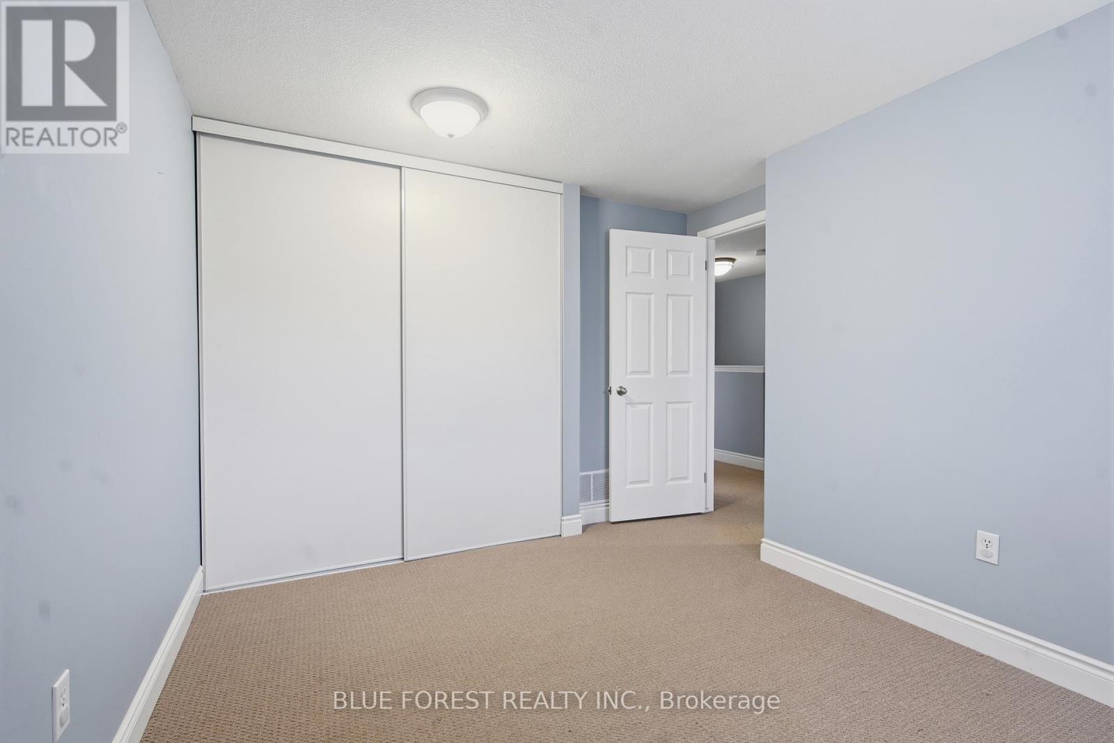 A bedroom with a white door and a carpeted floor.