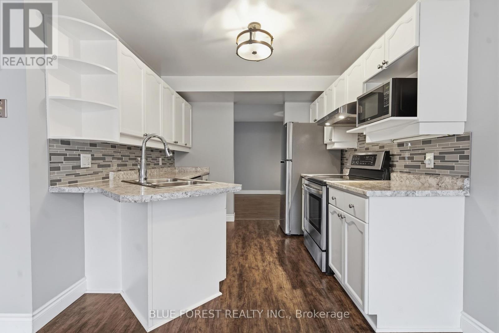 A kitchen with white cabinets and a marble countertop.