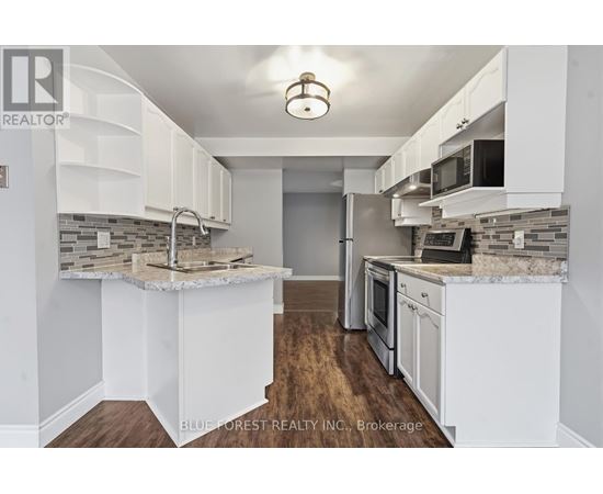 A kitchen with white cabinets and a marble countertop.