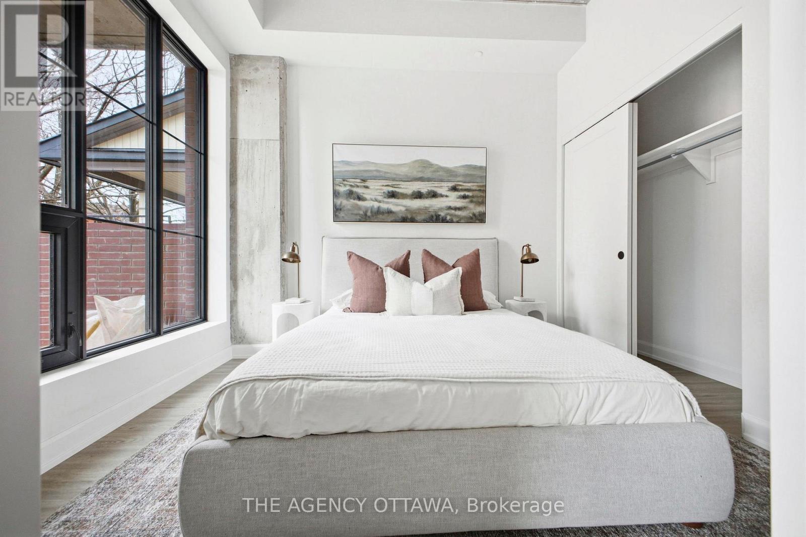 A bedroom with a large bed and a painting on the wall.