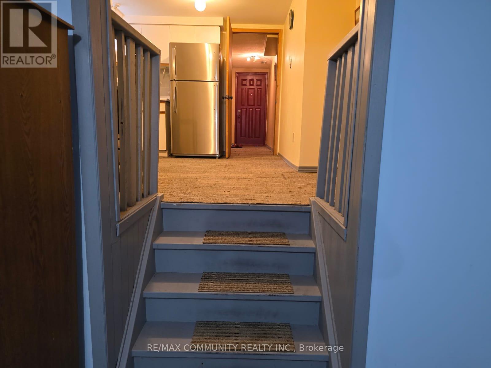 A hallway with a staircase leading to a kitchen area.