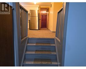 A hallway with a staircase leading to a kitchen area.