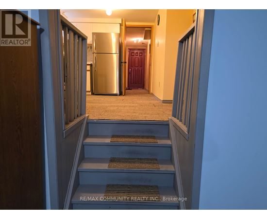 A hallway with a staircase leading to a kitchen area.