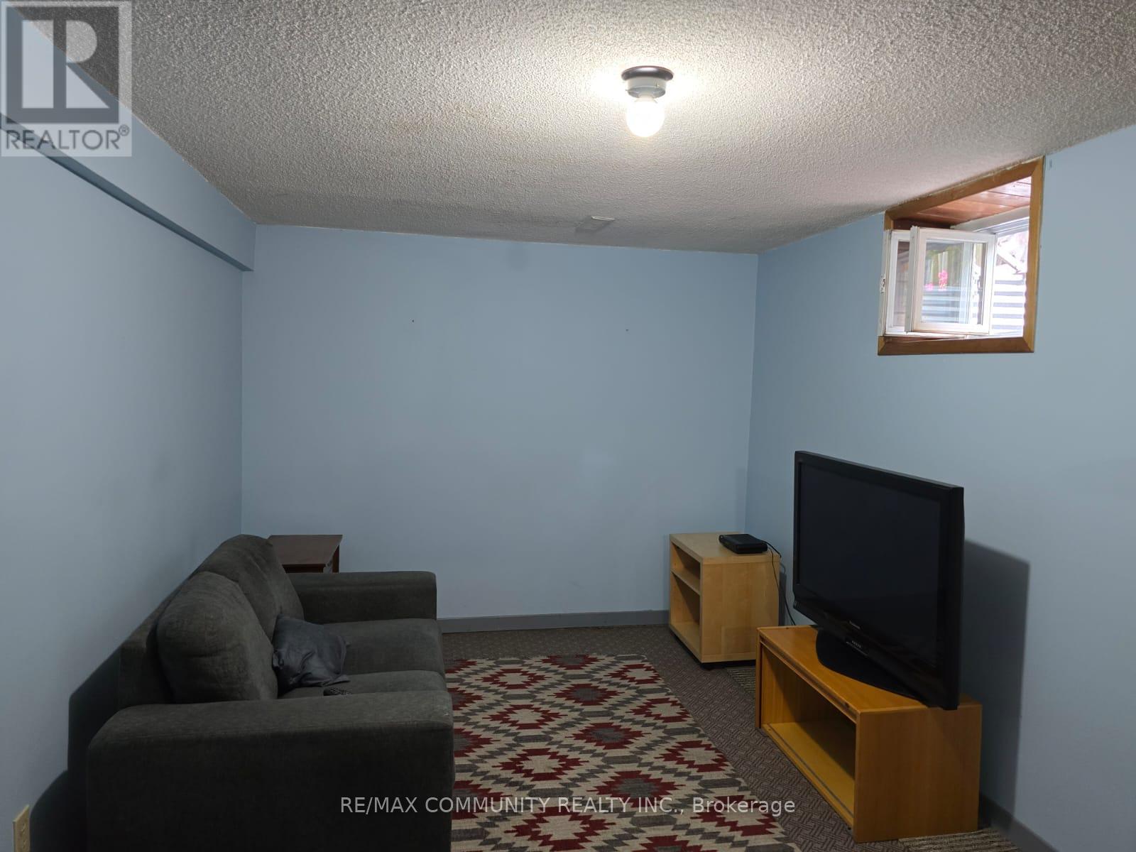 A living room with a grey couch, a black television, and a patterned carpet.