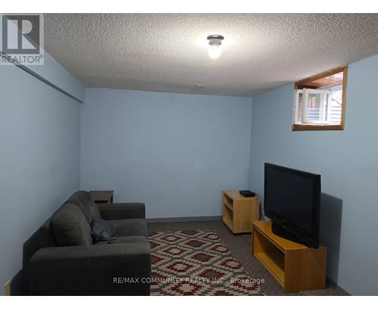 A living room with a grey couch, a black television, and a patterned carpet.