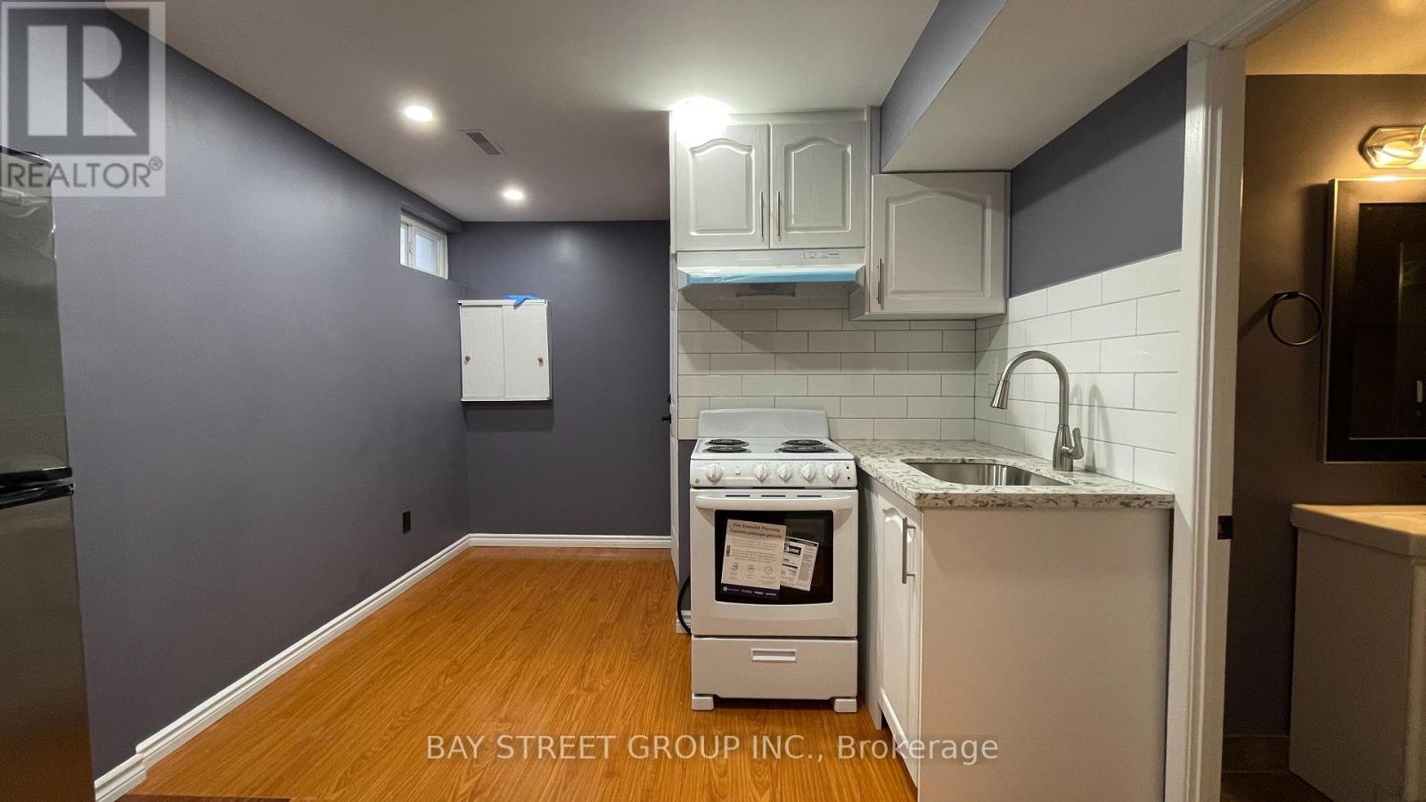 A kitchen with a refrigerator, oven, and sink.