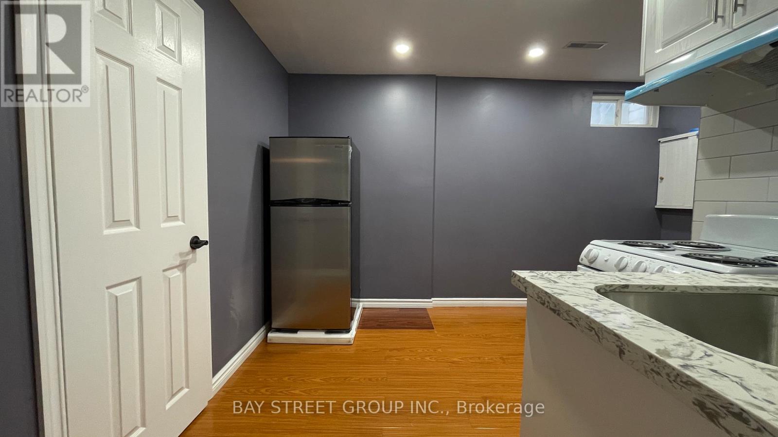 A kitchen with a white door, a refrigerator, and a counter.