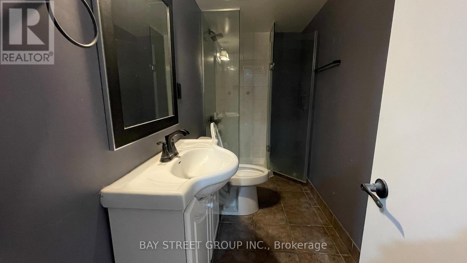 A white sink is in a small bathroom with a glass shower door.