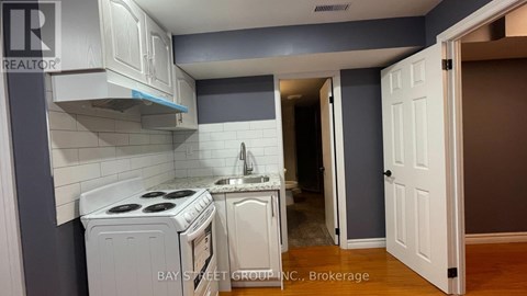 A kitchen with white appliances and cabinets in a realtor listing.