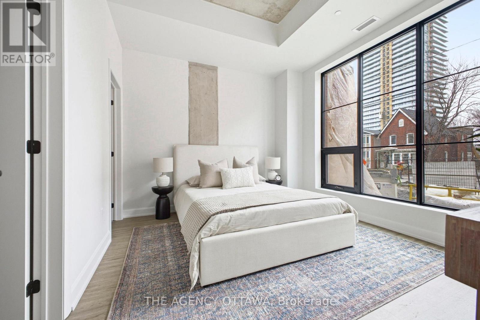 A bedroom with a large bed and a view of a construction site outside the window.