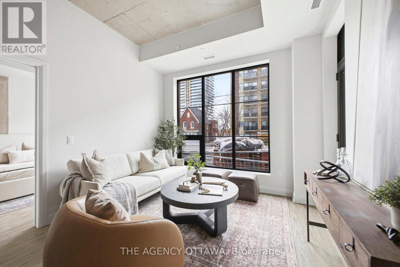 A well-lit, modern living room with a large window and a view of a building outside.
