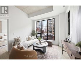 A well-lit, modern living room with a large window and a view of a building outside.