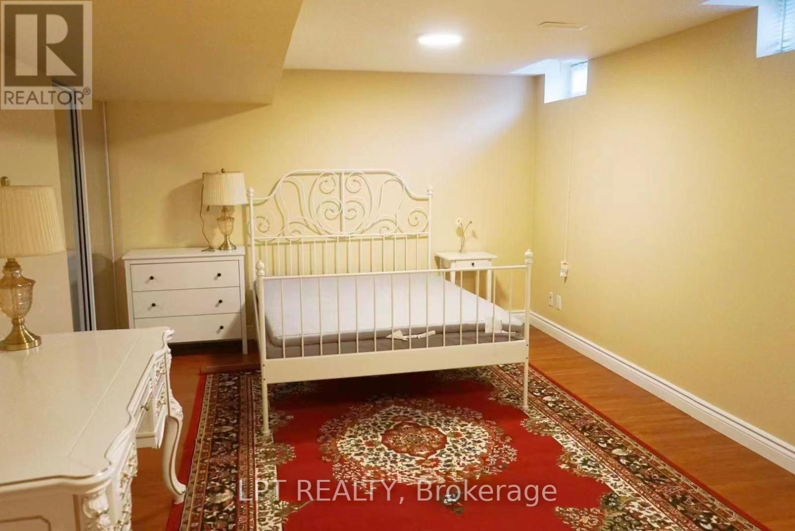 A bedroom with a white bed, dresser, and rug.