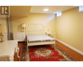 A bedroom with a white bed, dresser, and rug.