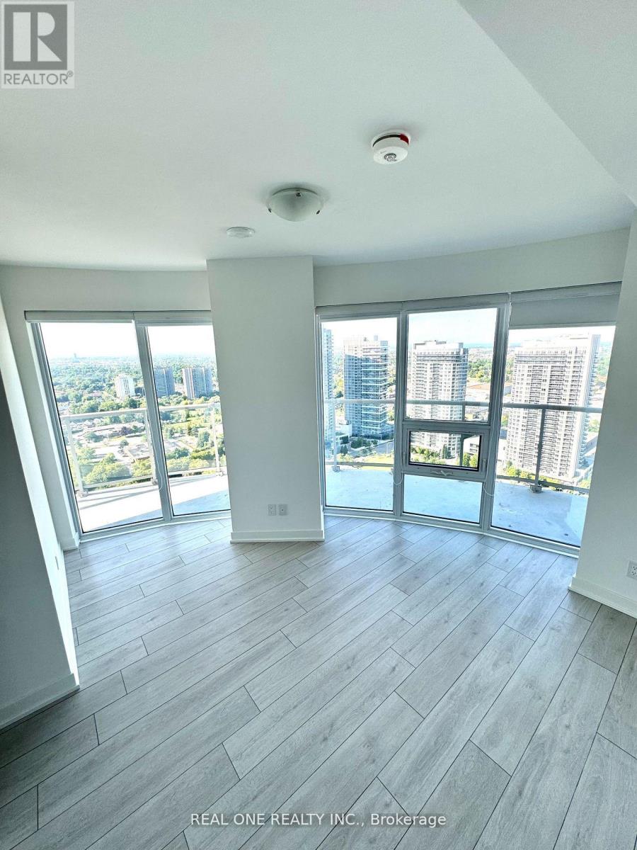 A spacious room with a view of the cityscape through large windows.