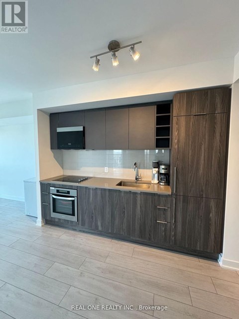 A modern kitchen with dark wood cabinets and a stainless steel island.