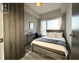 A bedroom with a bed, desk, and window.